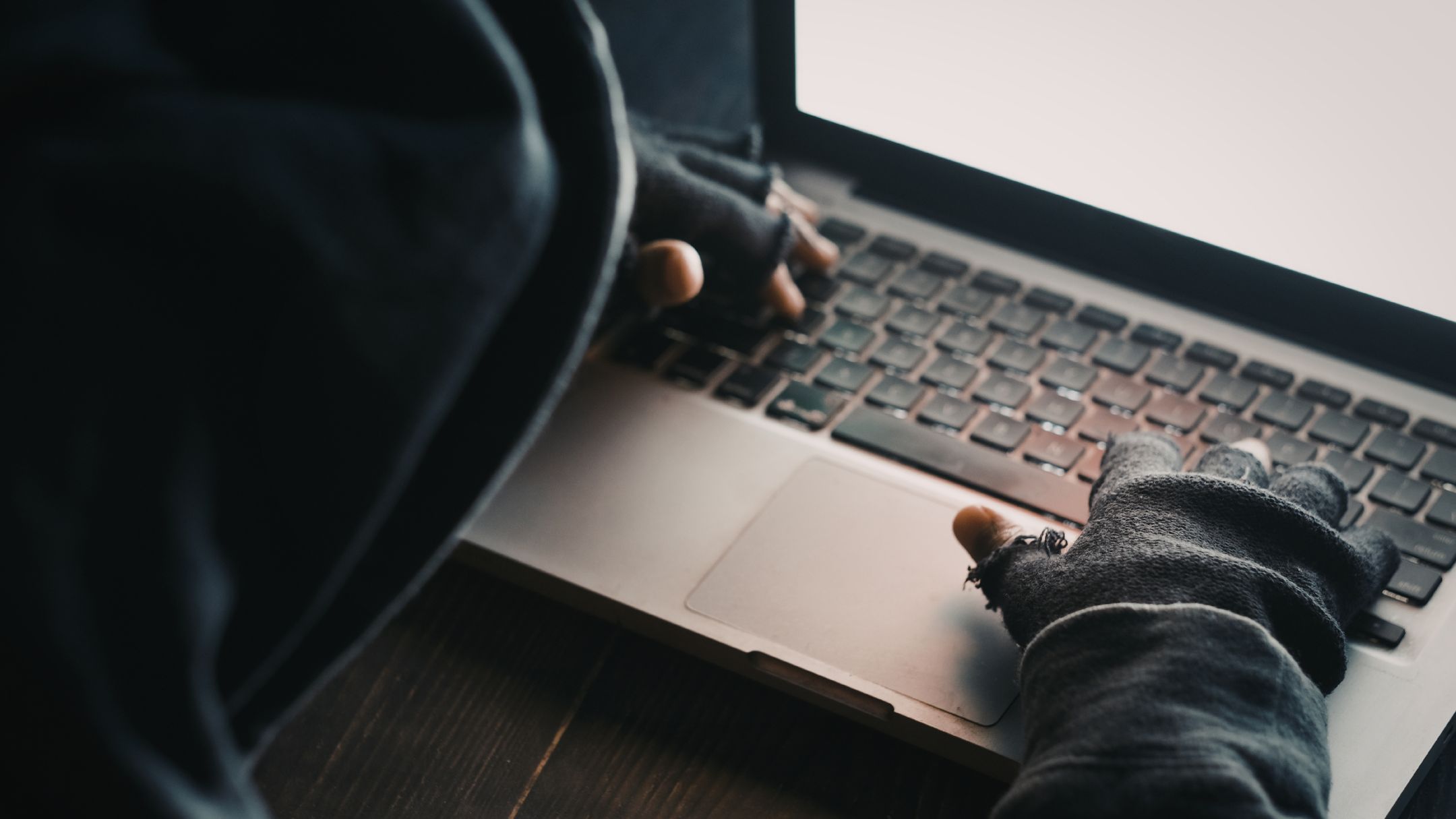 Atacante encapuchado frente a un portátil preparando un ataque de ransomware