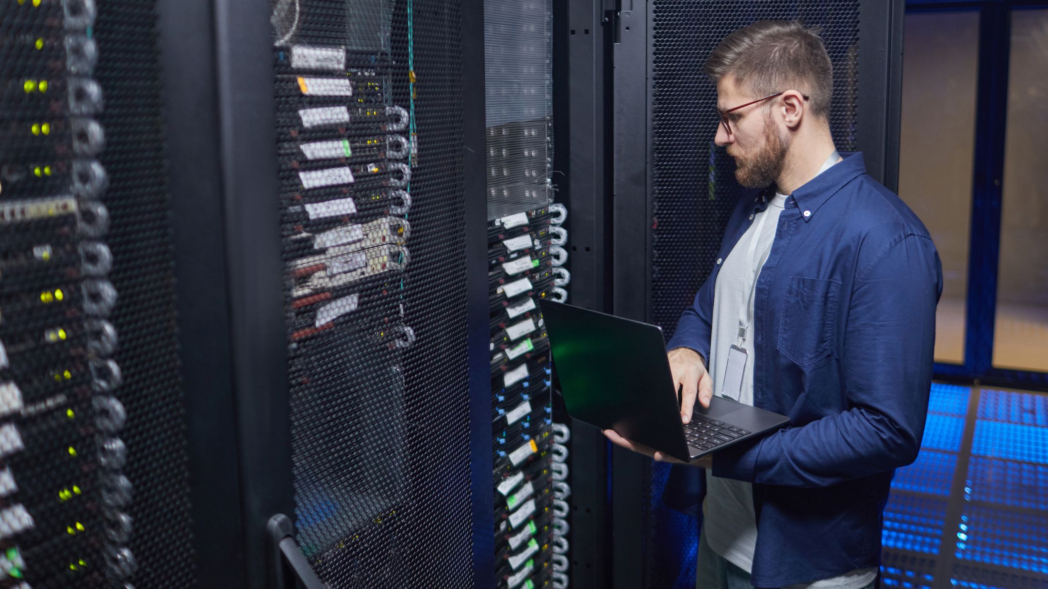 Técnico trabajando en un portátil junto a servidores en rack